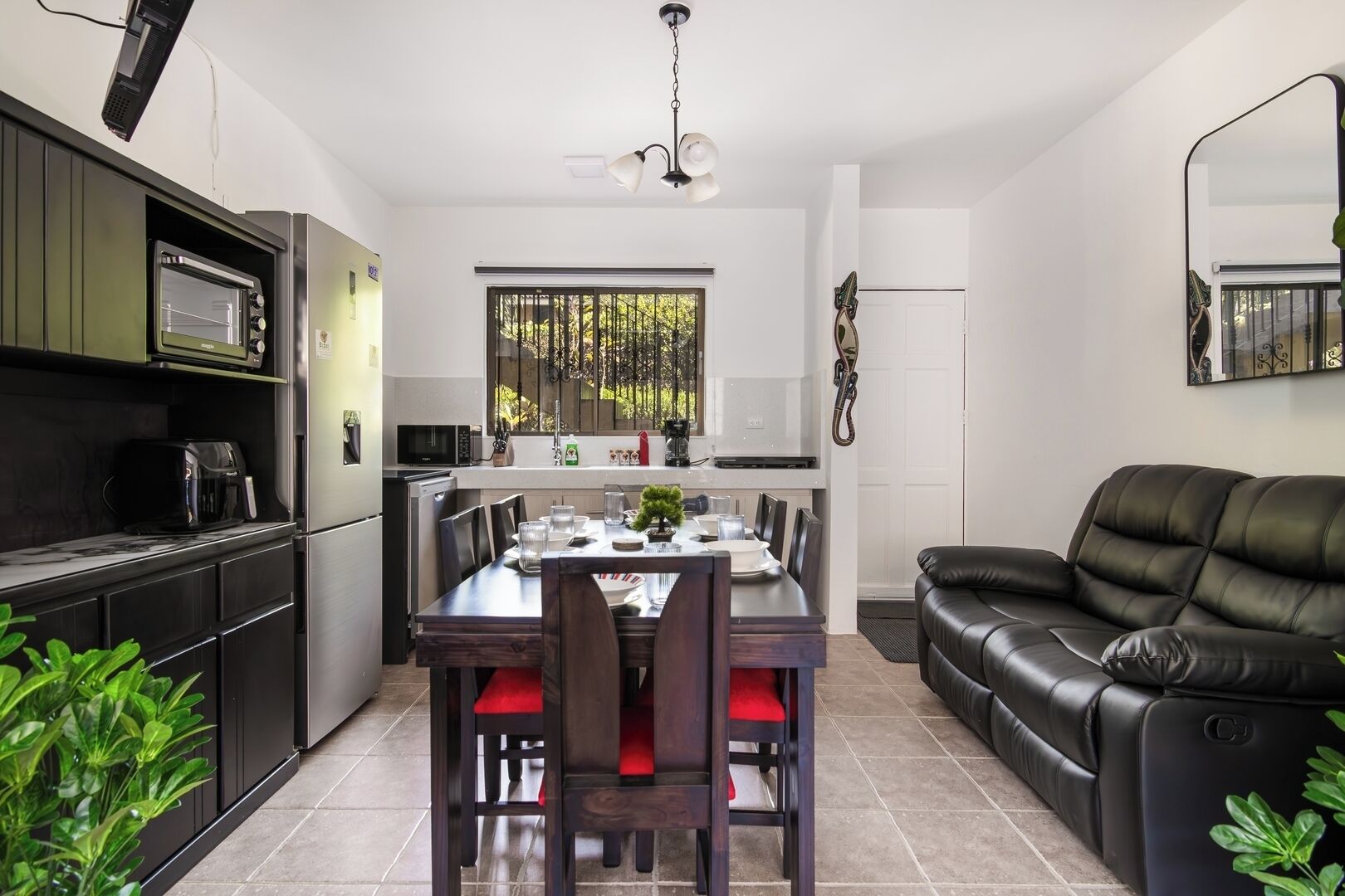 A modern kitchen with a dining area, a black leather sofa, and a ceiling fan.