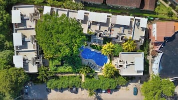 Eine Vogelperspektive eines Wohnkomplexes mit mehreren Gebäuden, einem Schwimmbad und umliegender Grünfläche.