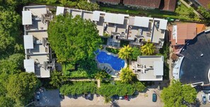 Eine Vogelperspektive eines Wohnkomplexes mit mehreren Gebäuden, einem Schwimmbad und umliegender Grünfläche.
