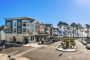 Uma rua costeira com edifícios de vários andares, um estacionamento e vista para o oceano.