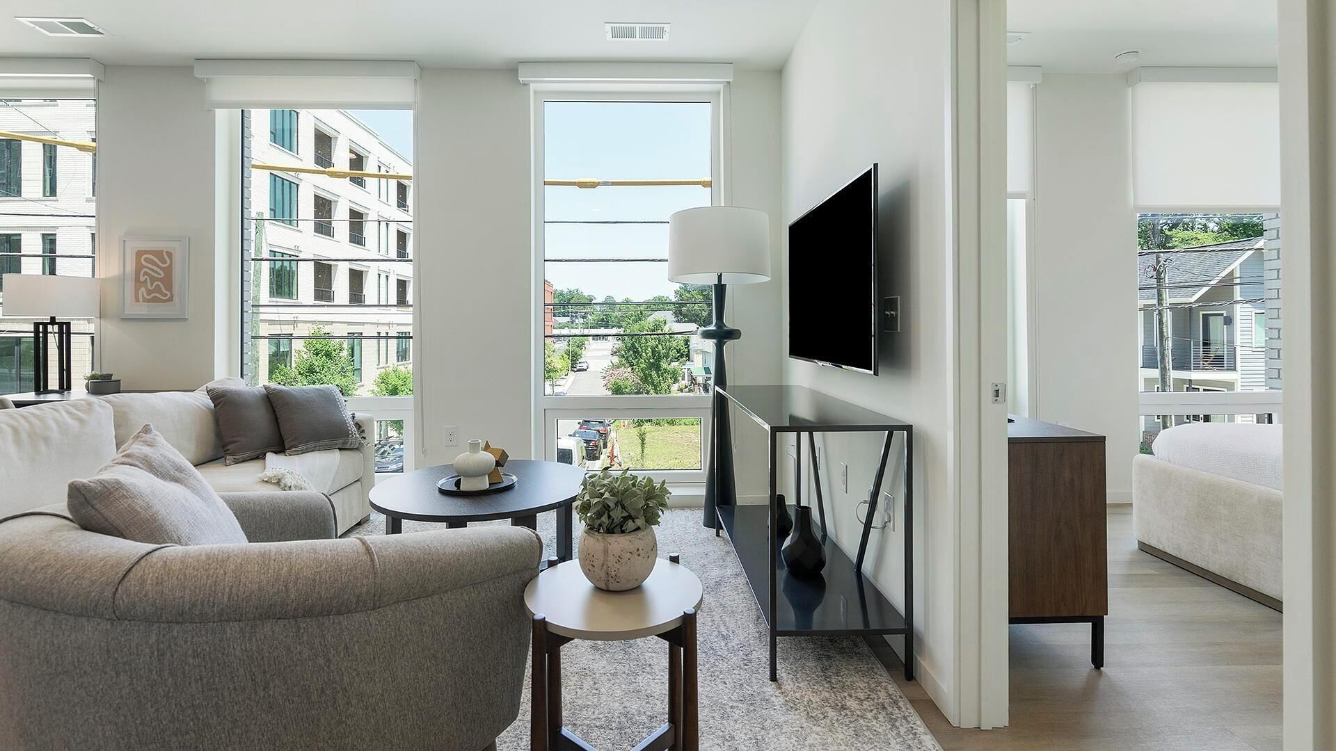 Una sala de estar moderna con un sofá, una mesa de centro, un televisor y vistas a una zona residencial.