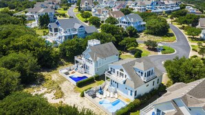 A residential area with houses, a swimming pool, and a curved road. - Currituck Club Retreat with Pool, Spa & Golf Views (Corolla)