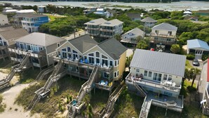 Un quartier résidentiel situé sur la côte, avec des maisons dotées de balcons et de passerelles en bois menant à la plage.