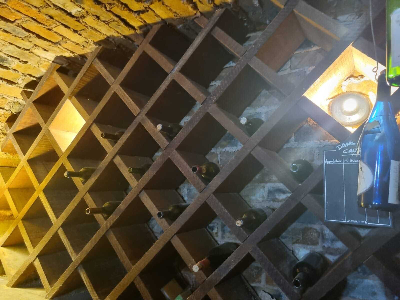 A wine cellar with a brick wall and a metal rack holding wine bottles.