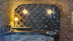 A brick-walled bar area with a wine rack, a table with vintage wine corks, and a lamp. - Casarão Hortência (Teresópolis)