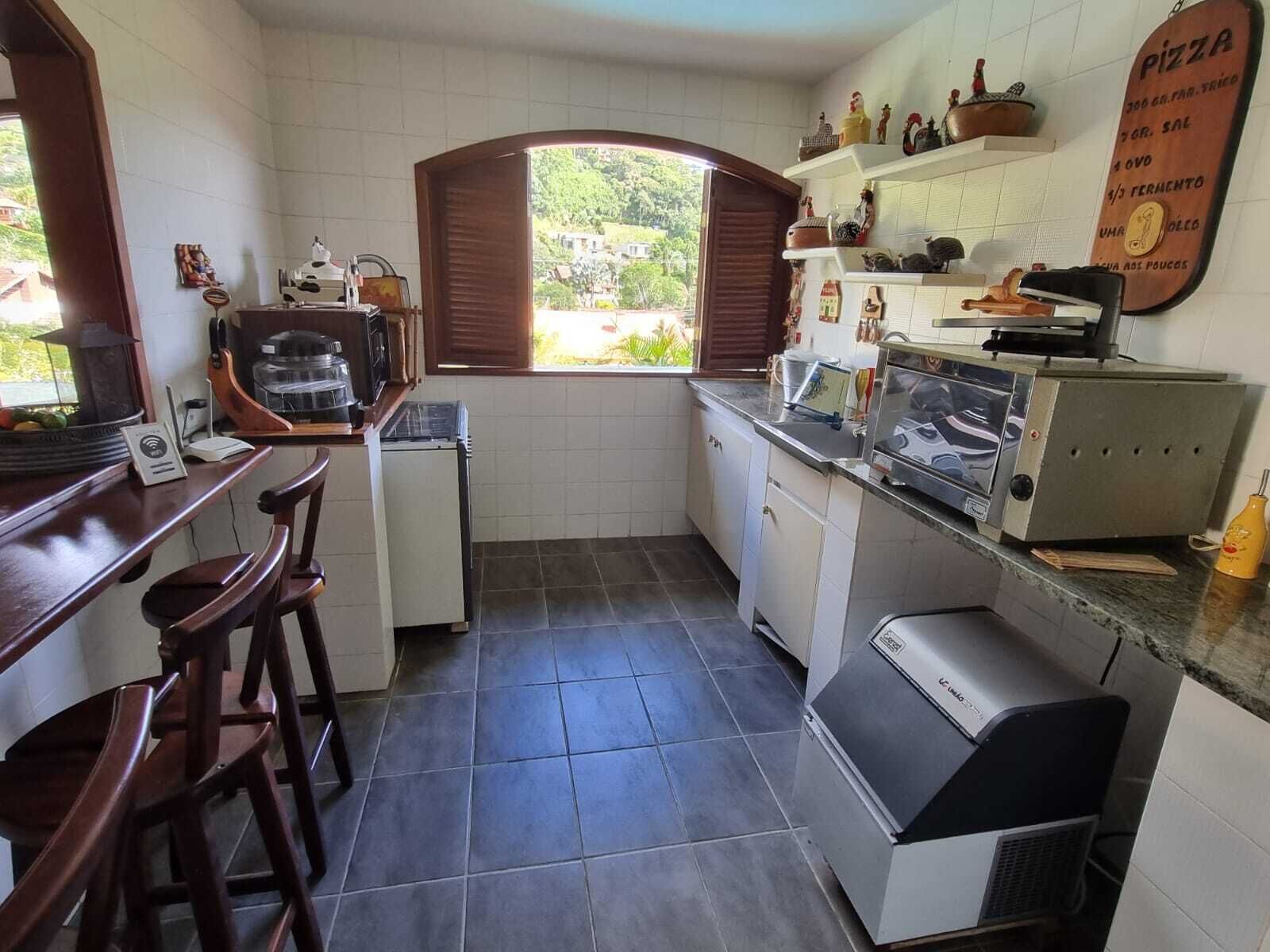 A compact kitchen with a window, a coffee machine, a small refrigerator, and a pizza menu on the wall.