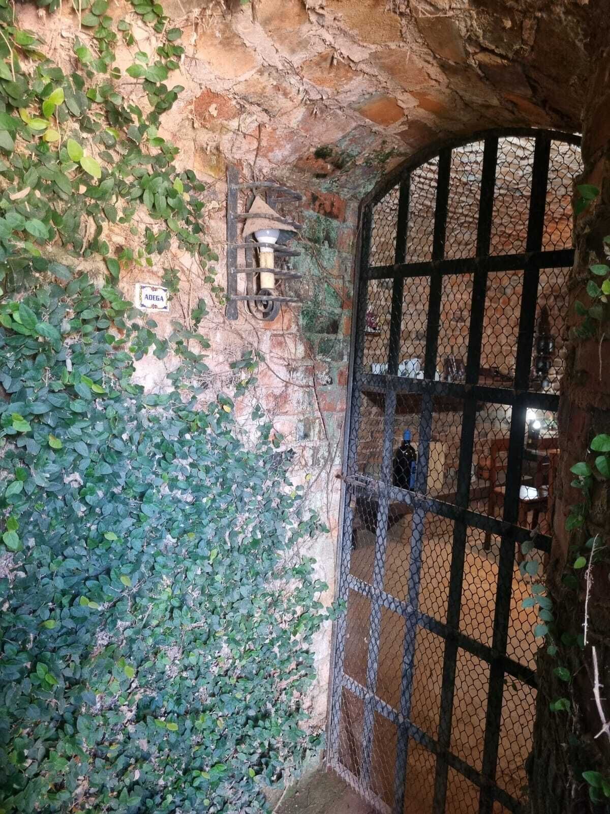 A stone wall with a metal gate, a small light fixture, and a sign reading 'ADEFGA'.