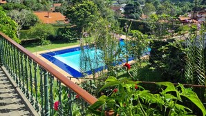 A pool with a view of a hillside and houses. - Casarão Hortência (Teresópolis)