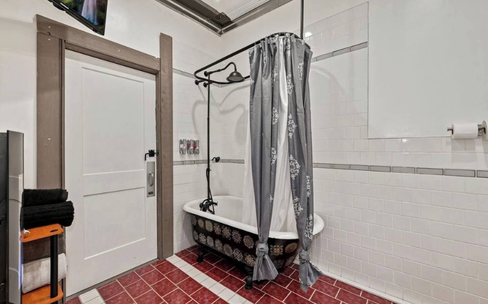 A bathroom with a shower, a bathtub, a toilet, and a door.