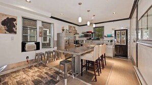 A modern kitchen with a central island, bar stools, a refrigerator, and a microwave.