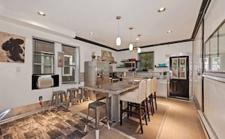 Una cocina moderna con una isla central, taburetes de bar, un refrigerador y un microondas.