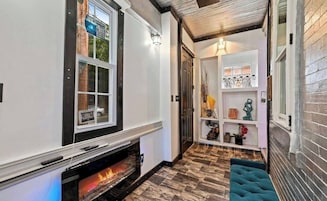 Un pasillo con chimenea, un estante con objetos decorativos y una puerta que da a otra habitación.
