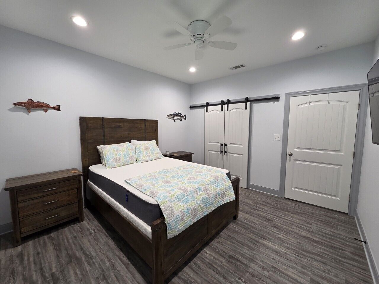 A bedroom with a bed, nightstands, a ceiling fan, and a wardrobe.