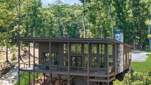 Uma cabana moderna com varanda, rodeada por uma floresta.