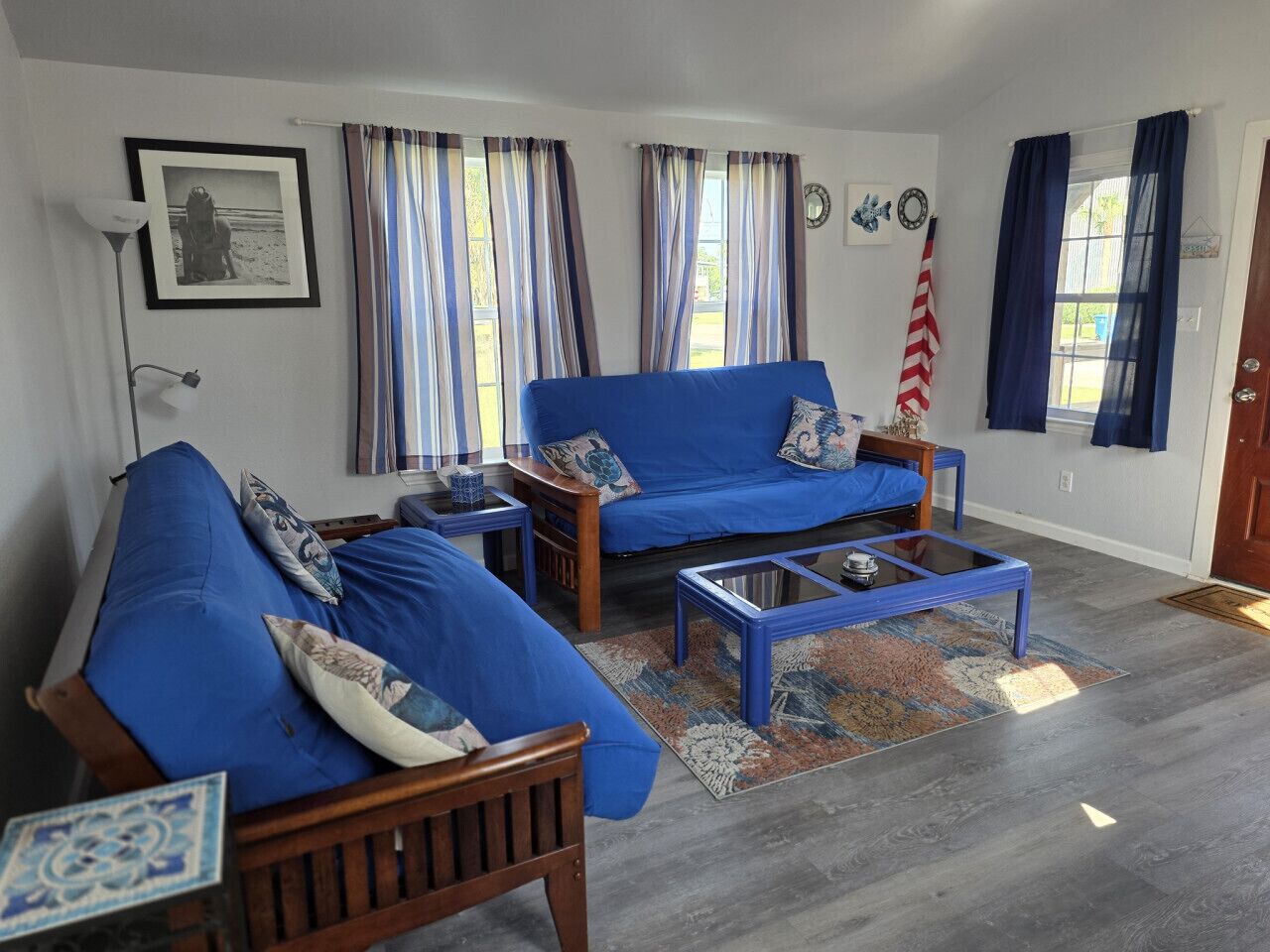A living room with two blue sofas, a coffee table, and striped curtains.