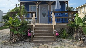 A small, single-story building with a blue exterior, a wooden front porch, and a sign reading 'Blue Bay Cottage.' - Tiny Home Walking Distance to the Beach (Port O`Connor)