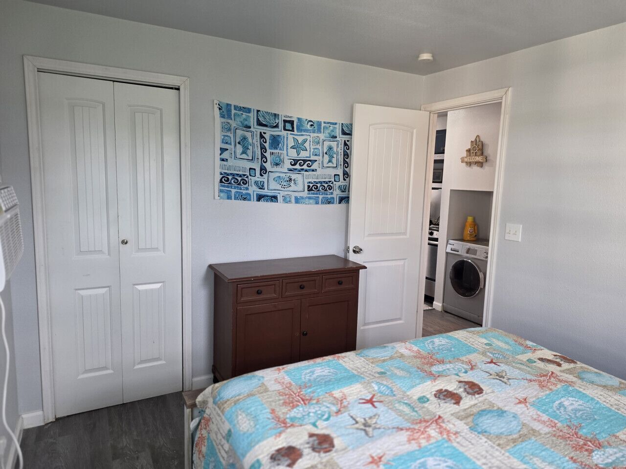 Une chambre à coucher avec un lit, une commode, un lave-linge et une porte.