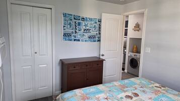 Une chambre à coucher avec un lit, une commode, un lave-linge et une porte.