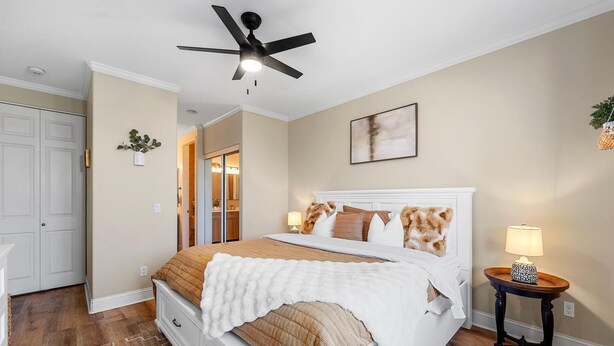 Une chambre à coucher avec un lit, un ventilateur de plafond, une table de chevet et une lampe.