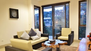 A living room with a sofa, armchairs, a coffee table, and large windows with a view of buildings. - Cempaka 2 Villa Dago Private Pool (Bandung)