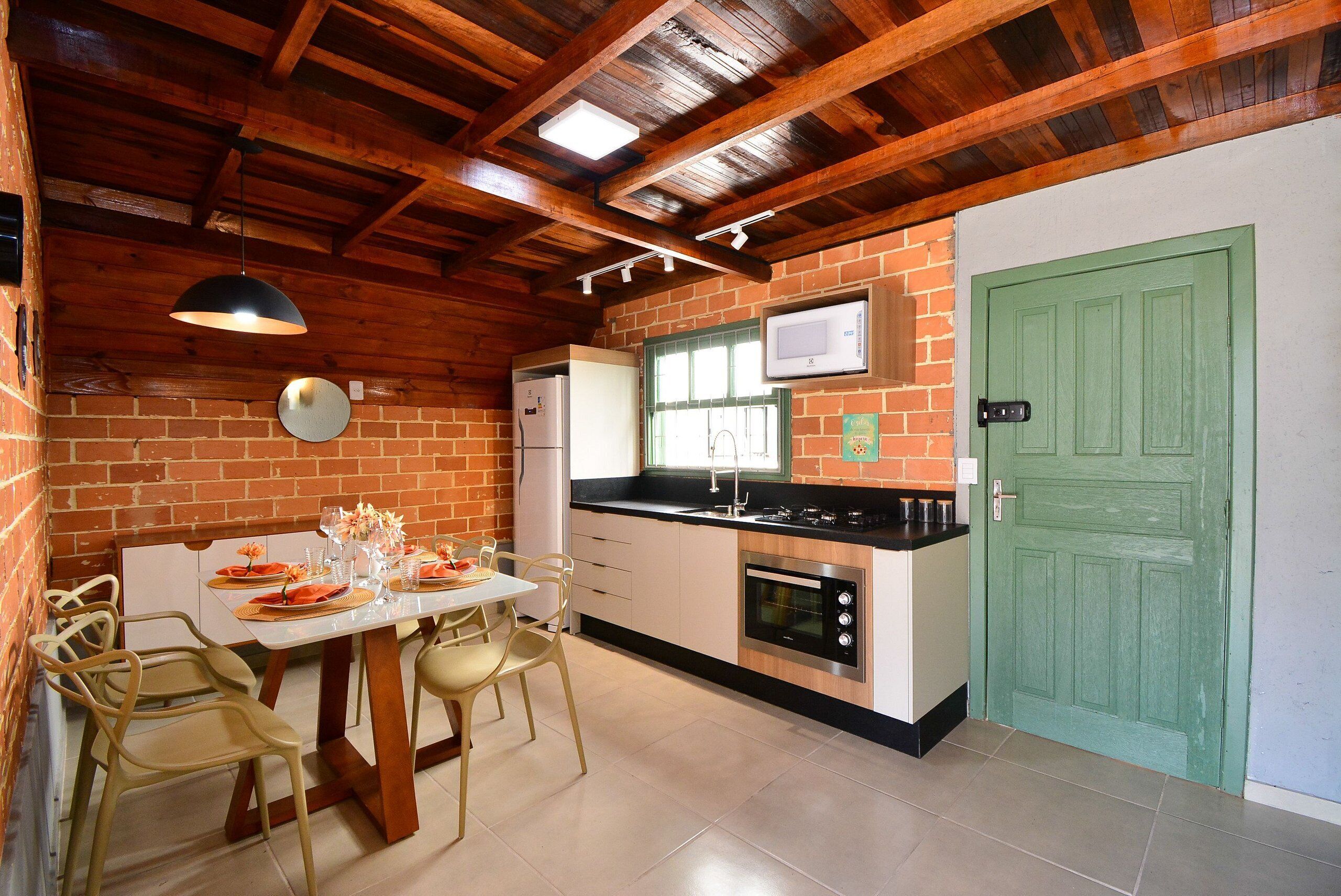 Uma cozinha com uma mesa de jantar, cadeiras, geladeira, forno e uma porta verde.