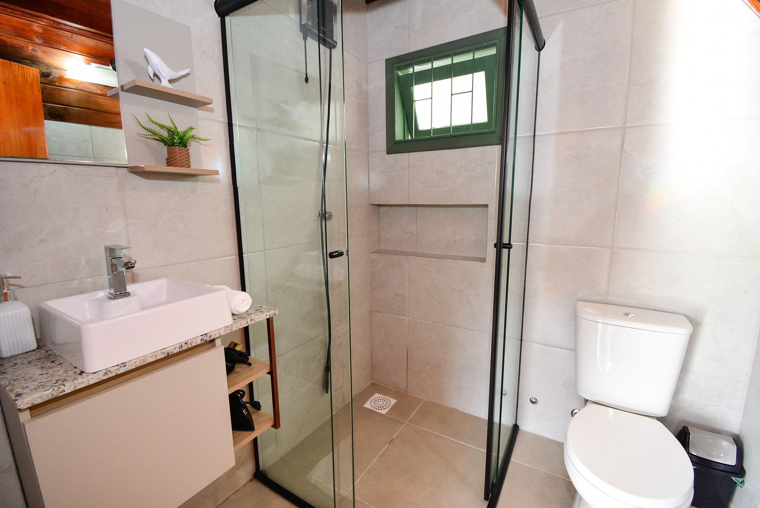 Un baño con ducha envuelta en vidrio, lavabo e inodoro.