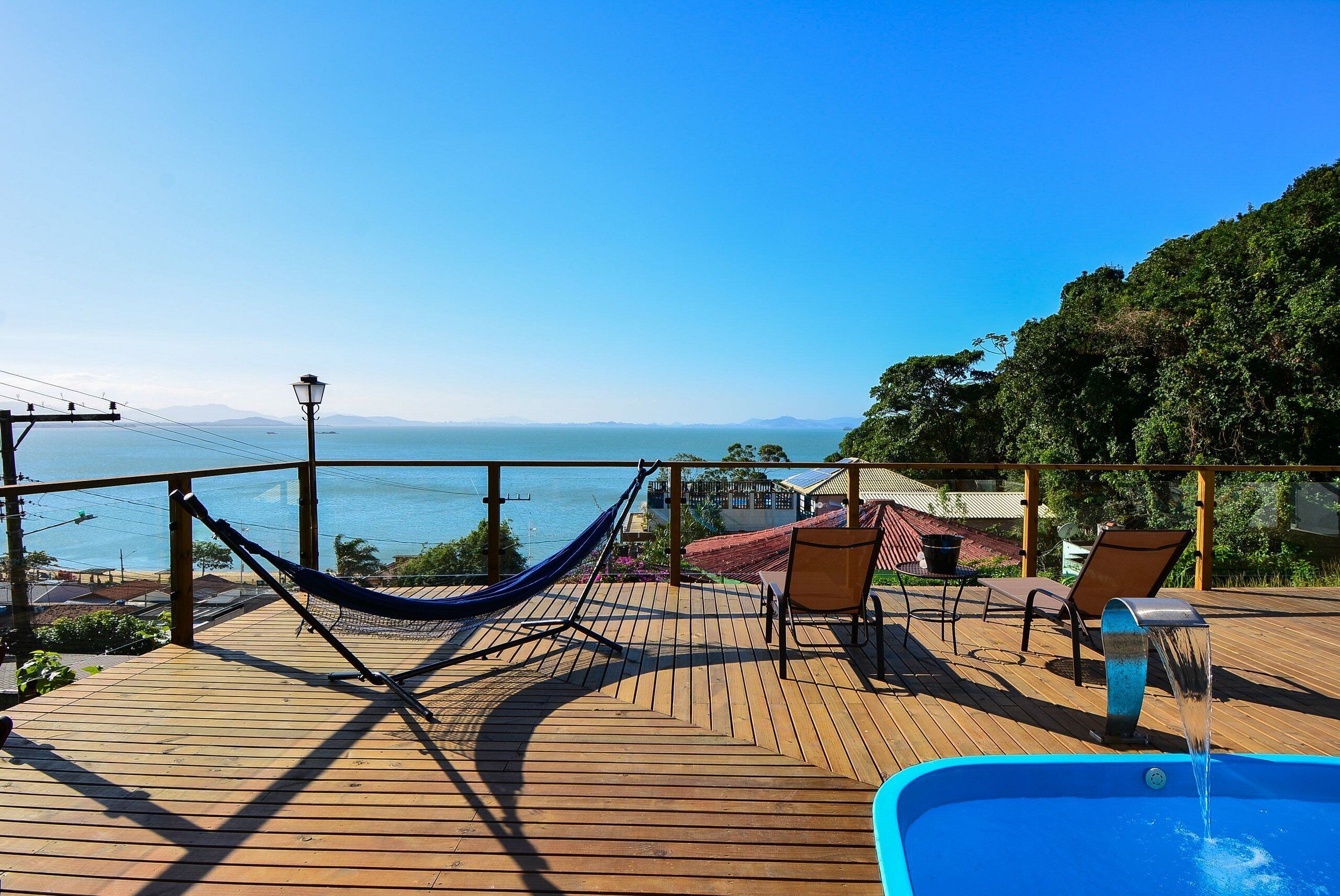 A wooden deck with a hammock, two chairs, and a small pool.