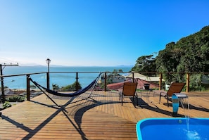 A wooden deck with a hammock, two chairs, and a small pool.
