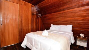 Um quarto com painéis de madeira, uma cama, uma mesa de cabeceira e uma pequena mesa com um vaso.