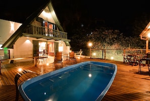 Un espace aménagé au bord de la piscine, avec une terrasse en bois, une piscine et un bâtiment doté d’un balcon.