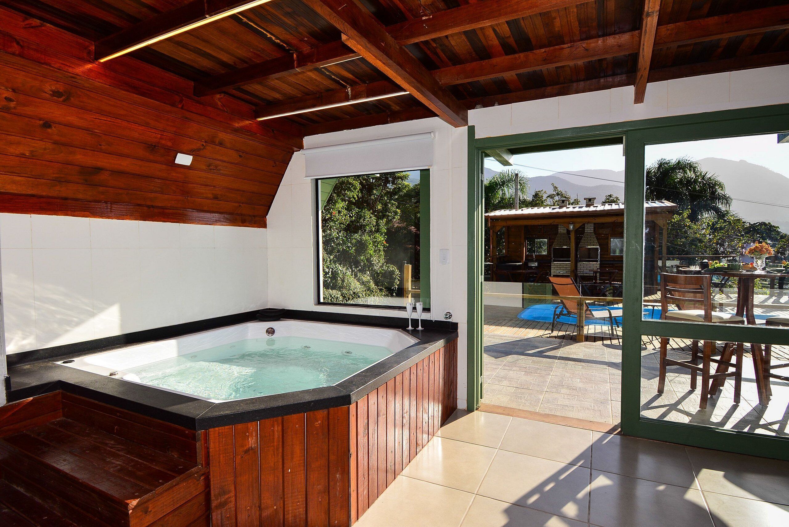 Un hidromasaje de madera con vista a una piscina y un área de estar exterior.