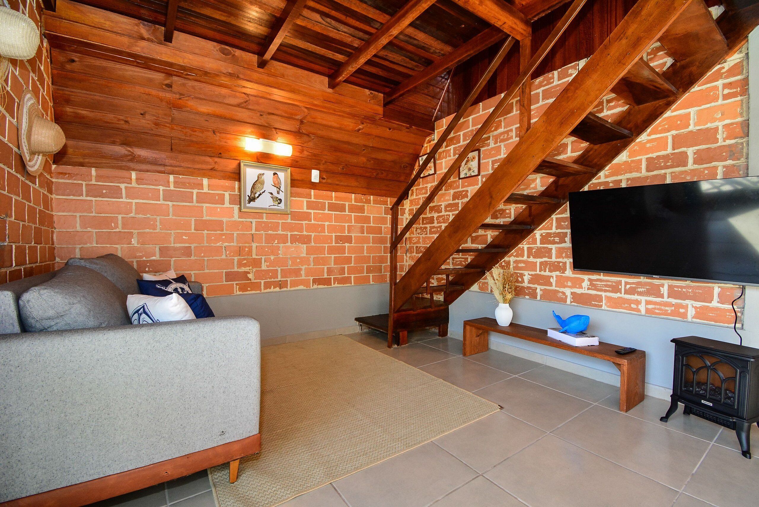 A living room with a sofa, a TV, a fireplace, and a brick wall.