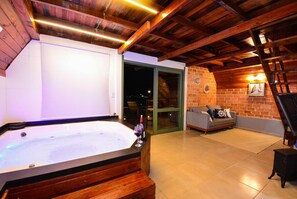 Un jacuzzi con un banco de madera, un sofá y una pared de ladrillo.