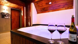 Interior em madeira com uma banheira de hidromassagem, duas taças de vinho e uma garrafa de vinho.