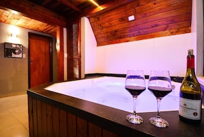 Un intérieur en bois avec un jacuzzi, deux verres à vin et une bouteille de vin.
