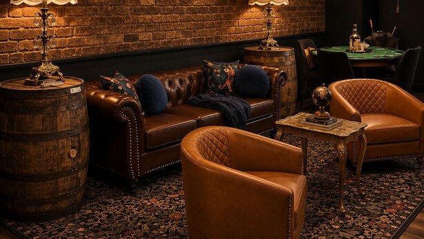 A cozy lounge with leather sofas, a patterned rug, and a brick wall.