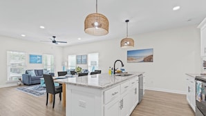 A spacious kitchen with a large island, white cabinetry, and a view of the beach. - Brand New 3 Bedroom in the Pines (Dauphin Island)