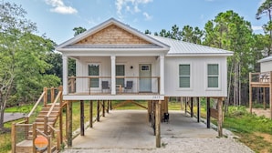 A two-story house with a balcony, wooden deck, and a number '1415' sign. - Brand New 3 Bedroom in the Pines (Dauphin Island)