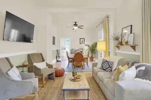 A living room with a TV, sofas, a coffee table, and a ceiling fan. - Bohemian Dream Hot Tub Bike Downtown Fire pit (Colorado Springs)