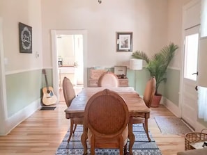 A dining area with a wooden table, chairs, a guitar, a framed picture, and a potted plant. - Bohemian Dream Hot Tub Bike Downtown Fire pit (Colorado Springs)