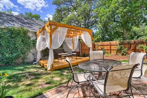 Ein Garten mit einer Holzpergola, Gartenmöbeln und einem Terrassentisch.
