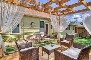 Eine überdachte Terrasse mit Korbmöbeln, einem Tisch und einem Stuhl.