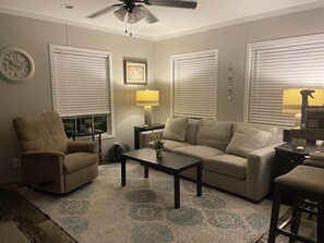 A living room with a sofa, armchair, coffee table, and a ceiling fan. - Great Escape! Beautiful 2-bedroom house in friendly Perdido Key. Pet friendly! (Pensacola)