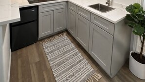 A modern kitchen with grey cabinets, a black dishwasher, a sink, and a wooden cutting board. - Private Studio in North Austin ~ Near The Domain, AC & Free Parking (Austin)