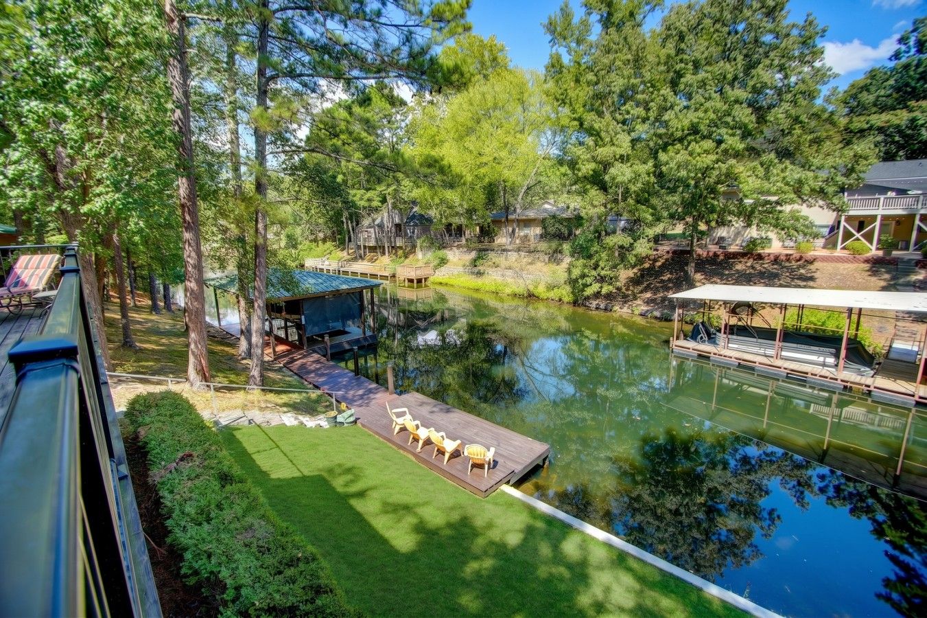 A lakeside property with a dock, outdoor seating, and a boat.