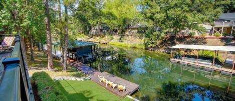 A lakeside property with a dock, outdoor seating, and a boat.
