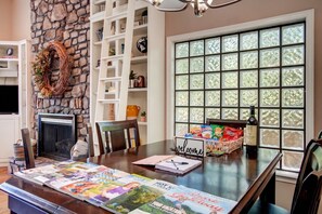A cozy living room with a fireplace, a stone wall, a bookshelf, and a large window with frosted glass. - Lake Hamilton Retreat w Private Dock & Deck (Hot Springs)