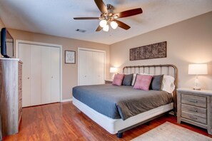 A bedroom with a bed, bedside tables, a ceiling fan, and a wall-mounted artwork. - Lake Hamilton Retreat w Private Dock & Deck (Hot Springs)