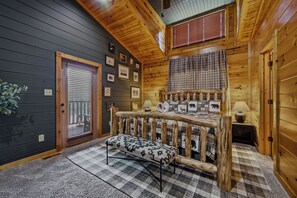A cozy cabin room with a bed, a bench, and a window with blinds. - MT Views Cozy, Well Appointed Hot Tub + Game Room, 1.5 Mi to Downtown, Sleeps 10 (Gatlinburg)