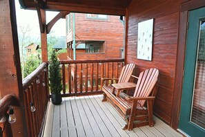 A wooden deck with a bench and chairs, a potted plant, and a door with a window. - MT Views Cozy, Well Appointed Hot Tub + Game Room, 1.5 Mi to Downtown, Sleeps 10 (Gatlinburg)